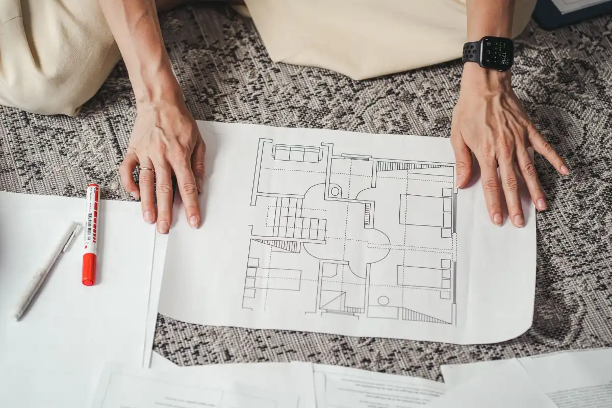 Mains posées sur les plans d’une maison préparés pour une demande de permis
