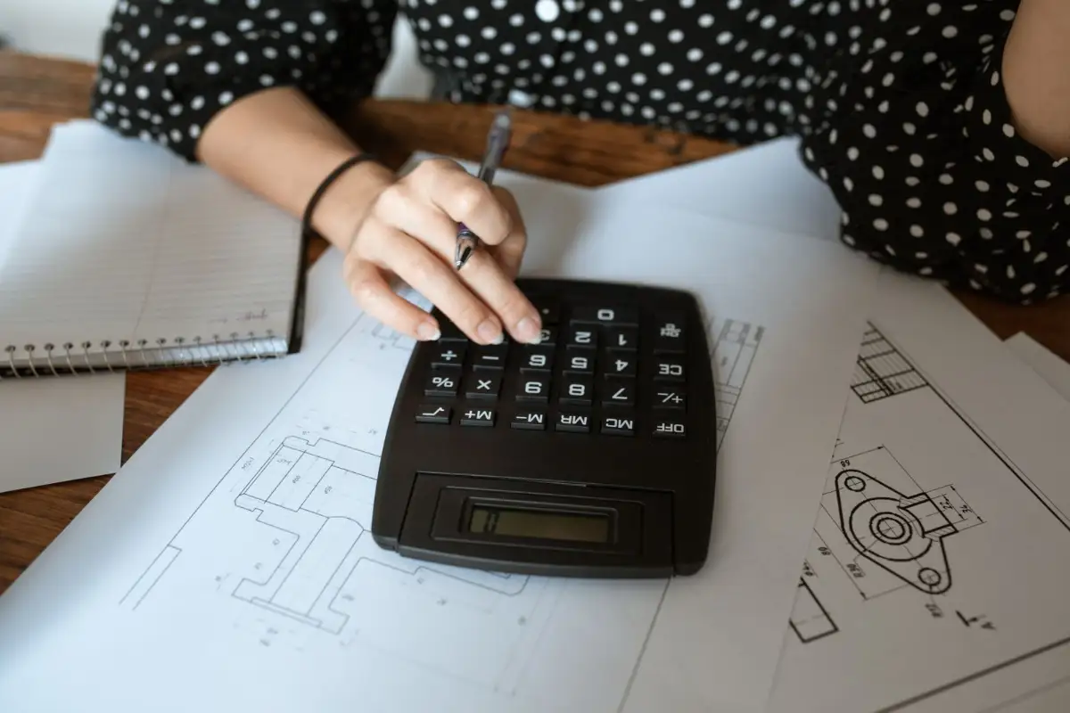 Calcul du prix des travaux avec une calculatrice posée sur des plans de construction